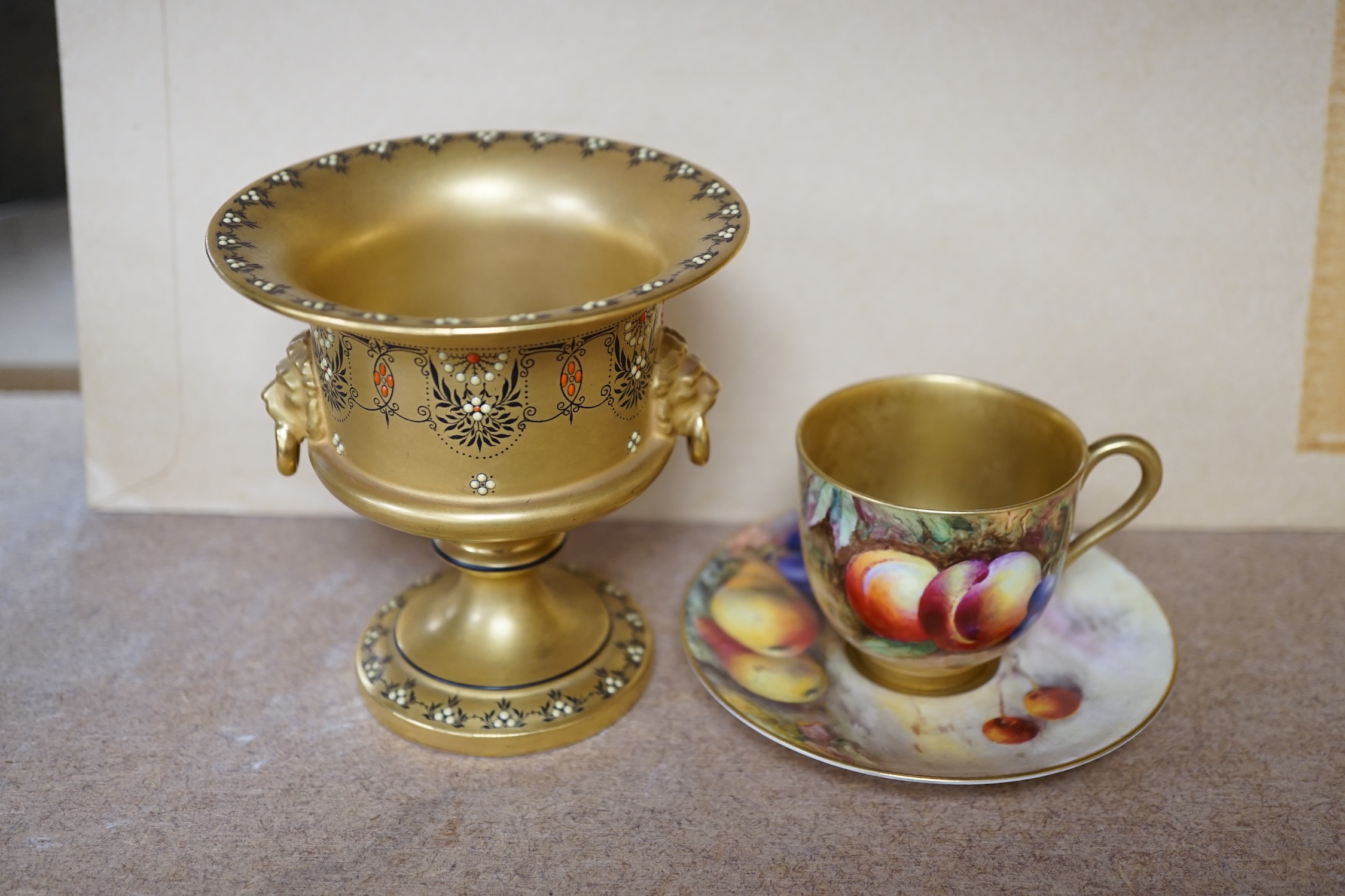 A Royal Worcester miniature fruit painted cup and saucer, Hale and Everett, and an unusual gilded campana vase, 10cm high. Condition - saucer cracked, otherwise good